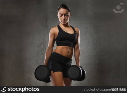 fitness, sport, exercising, training and people concept - young woman flexing muscles with dumbbells in gym