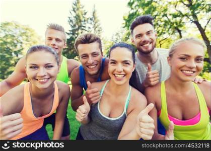 fitness, sport, friendship and healthy lifestyle concept - group of happy teenage friends showing thumbs up outdoors