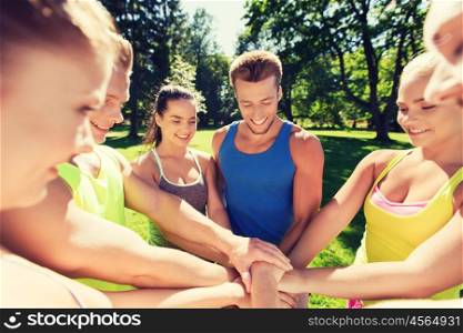 fitness, sport, friendship and healthy lifestyle concept - group of happy teenage friends with hands on top outdoors