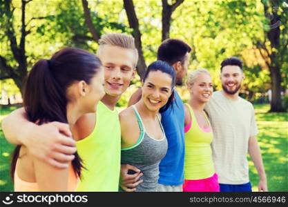 fitness, sport, friendship and healthy lifestyle concept - group of happy teenage friends or sportsmen hugging and talking outdoors