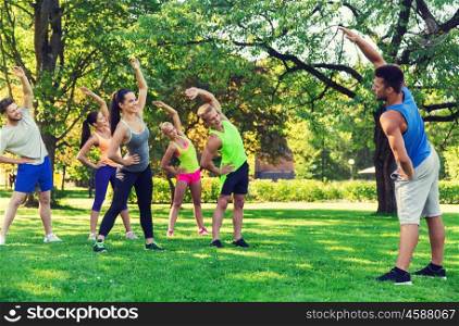 fitness, sport, friendship and healthy lifestyle concept - group of happy teenage friends or sportsmen exercising and stretching hands at boot camp