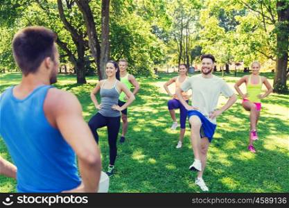 fitness, sport, friendship and healthy lifestyle concept - group of happy teenage friends or sportsmen exercising and raising legs at boot camp