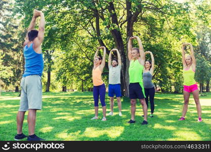 fitness, sport, friendship and healthy lifestyle concept - group of happy teenage friends or sportsmen exercising and stretching hands up at boot camp