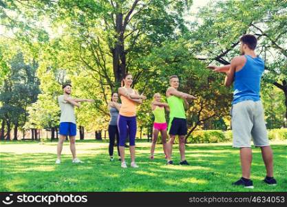 fitness, sport, friendship and healthy lifestyle concept - group of happy teenage friends or sportsmen exercising and stretching hands at boot camp