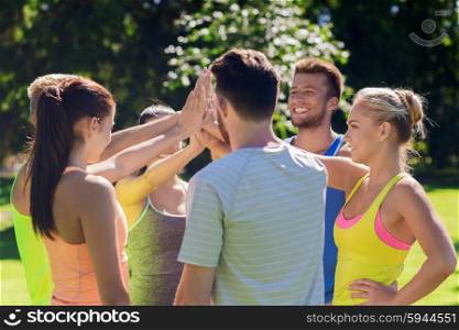 fitness, sport, friendship and healthy lifestyle concept - group of happy teenage friends or sportsmen making high five outdoors
