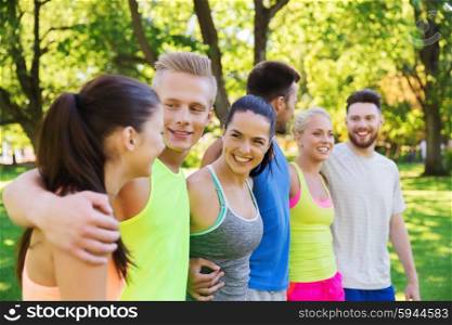 fitness, sport, friendship and healthy lifestyle concept - group of happy teenage friends or sportsmen hugging and talking outdoors