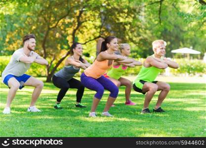 fitness, sport, friendship and healthy lifestyle concept - group of happy teenage friends or sportsmen exercising and doing squats at boot camp