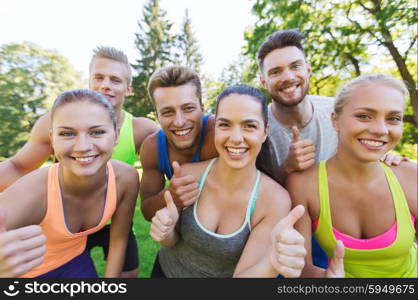fitness, sport, friendship and healthy lifestyle concept - group of happy teenage friends showing thumbs up outdoors