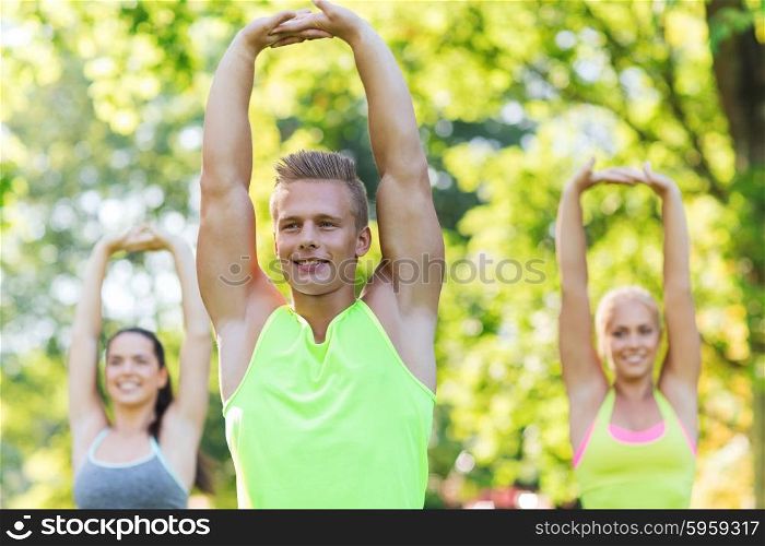 fitness, sport, friendship and healthy lifestyle concept - group of happy teenage friends or sportsmen exercising and stretching hands up at boot camp