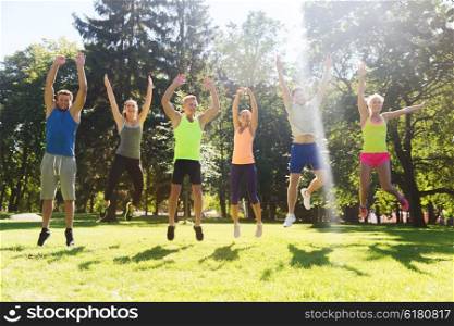 fitness, sport, friendship and healthy lifestyle concept - group of happy teenage friends or sportsmen jumping high outdoors