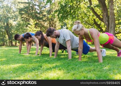 fitness, sport, friendship and healthy lifestyle concept - group of teenage friends or sportsmen exercising and doing push-ups at boot camp