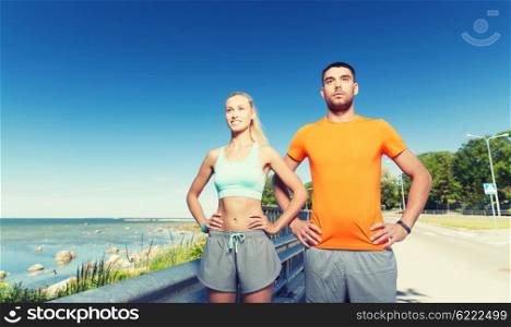 fitness, sport, friendship and healthy lifestyle concept - happy couple exercising at summer seaside