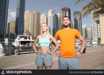 fitness, sport, friendship and healthy lifestyle concept - happy couple exercising over dubai city street background
