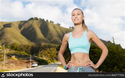 fitness, sport, friendship and healthy lifestyle concept - happy young woman doing sports over big sur hills and road background in california. happy young woman doing sports outdoors. happy young woman doing sports outdoors