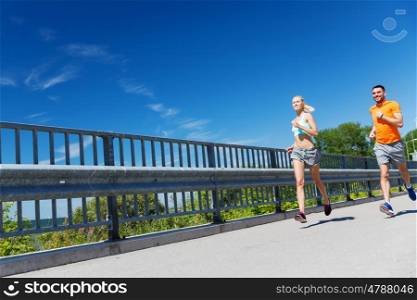 fitness, sport, friendship and healthy lifestyle concept - smiling couple running at summer seaside