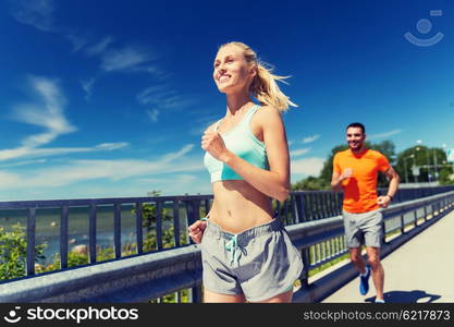 fitness, sport, friendship and healthy lifestyle concept - smiling couple running at summer seaside