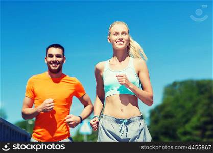 fitness, sport, friendship and healthy lifestyle concept - smiling couple running outdoors