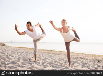 fitness, sport, friendship and lifestyle concept - couple making yoga exercises on beach