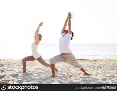 fitness, sport, friendship and lifestyle concept - couple making yoga exercises on beach
