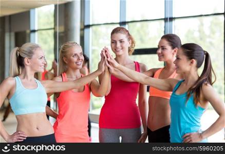 fitness, sport, friendship and lifestyle concept - group of women making high five gesture in gym