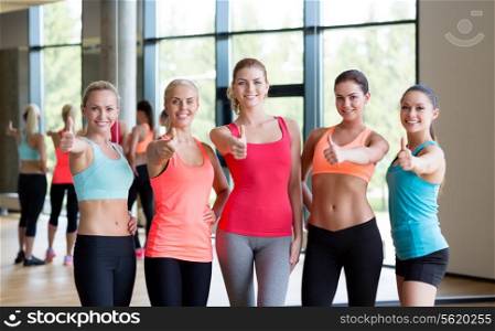 fitness, sport, friendship and lifestyle concept - group of women showing thumbs up gesture in gym