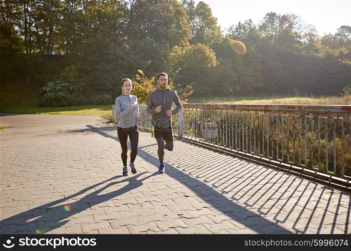 fitness, sport, friendship and lifestyle concept - happy couple running outdoors