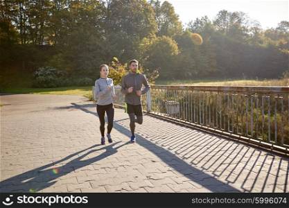 fitness, sport, friendship and lifestyle concept - happy couple running outdoors