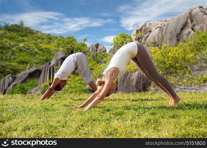 fitness, sport, friendship and lifestyle concept - smiling couple making yoga exercises outdoors over natural background. smiling couple making yoga exercises outdoors