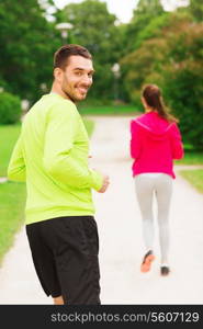 fitness, sport, friendship and lifestyle concept - smiling couple running outdoors