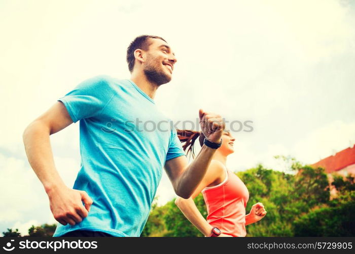 fitness, sport, friendship and lifestyle concept - smiling couple running outdoors