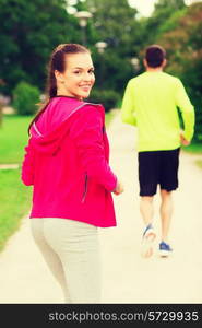 fitness, sport, friendship and lifestyle concept - smiling couple running outdoors