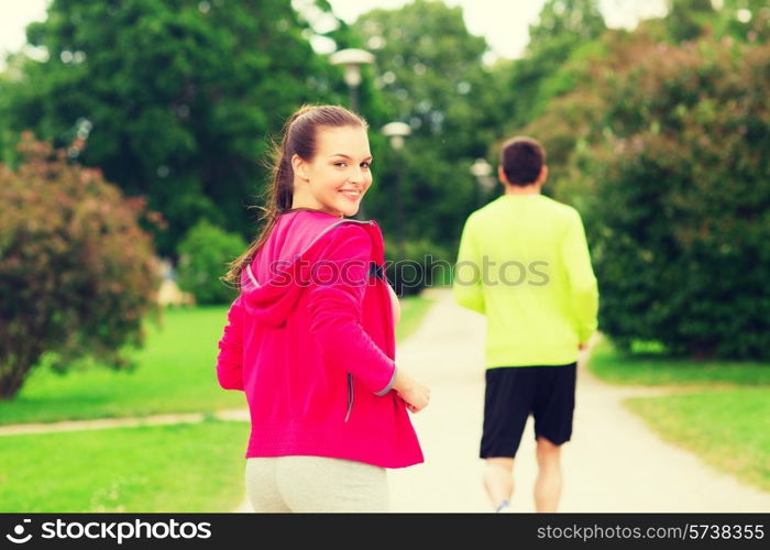 fitness, sport, friendship and lifestyle concept - smiling couple running outdoors