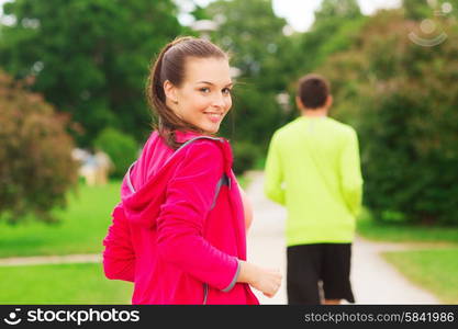 fitness, sport, friendship and lifestyle concept - smiling couple running outdoors