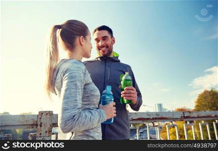 fitness, sport, friendship and lifestyle concept - smiling couple with bottles of water outdoors. smiling couple with bottles of water outdoors