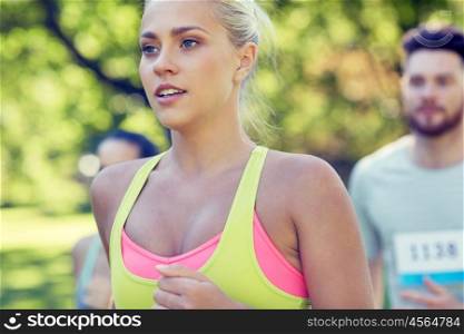 fitness, sport, friendship, race and healthy lifestyle concept - group of happy teenage friends or sportsmen running marathon with badge numbers outdoors