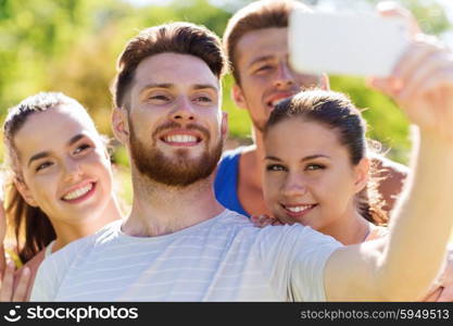 fitness, sport, friendship, technology and healthy lifestyle concept - group of happy teenage friends taking selfie with smartphone outdoors