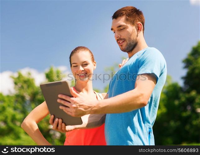 fitness, sport, friendship, technology and lifestyle concept - smiling couple with tablet pc computer outdoors