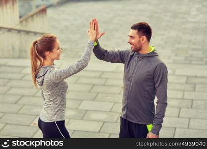 fitness, sport, gesture, people and success concept - happy couple giving high five outdoors. happy couple giving high five outdoors