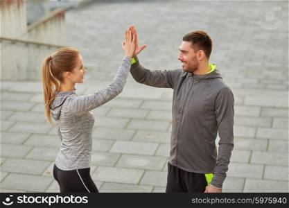 fitness, sport, gesture, people and success concept - happy couple giving high five outdoors