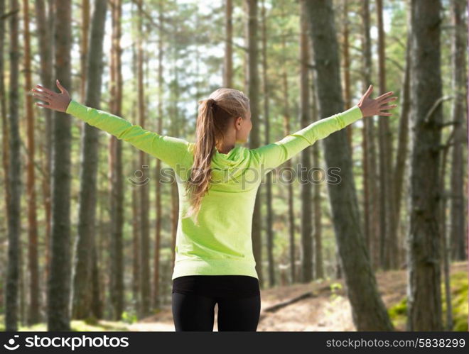 fitness, sport, happiness and people concept - happy woman raising hands over woods background from back