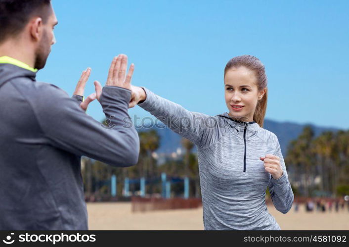 fitness, sport, martial arts and people concept - happy woman with personal trainer working on strike over venice beach background in california. happy woman with coach working on strike outdoors. happy woman with coach working on strike outdoors