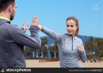 fitness, sport, martial arts and people concept - happy woman with personal trainer working on strike over venice beach background in california. happy woman with coach working on strike outdoors. happy woman with coach working on strike outdoors