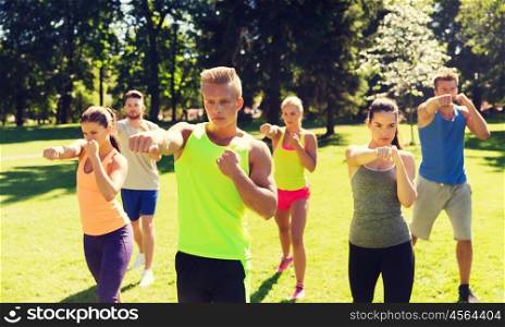 fitness, sport, martial arts, self-defense and healthy lifestyle concept - group of teenage friends or sportsmen exercising and at boot camp. group of friends or sportsmen exercising outdoors