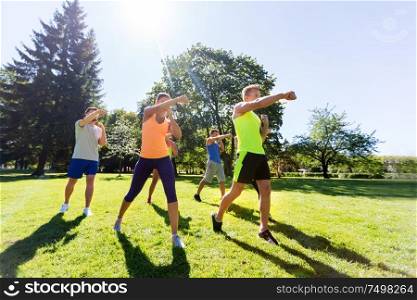 fitness, sport, martial arts, self-defense and healthy lifestyle concept - group of people or sportsmen exercising at boot camp in summer park. group of friends or sportsmen exercising at park