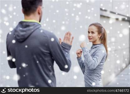 fitness, sport, martial arts, self-defense and people concept - happy woman with personal trainer working out strike outdoors over snow