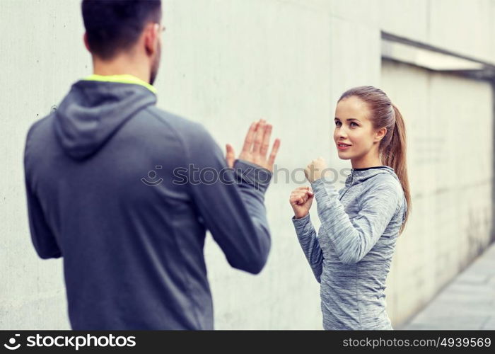 fitness, sport, martial arts, self-defense and people concept - happy woman with personal trainer working out strike outdoors. happy woman with coach working out strike outdoors