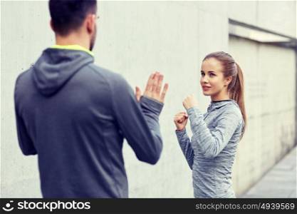 fitness, sport, martial arts, self-defense and people concept - happy woman with personal trainer working out strike outdoors. happy woman with coach working out strike outdoors