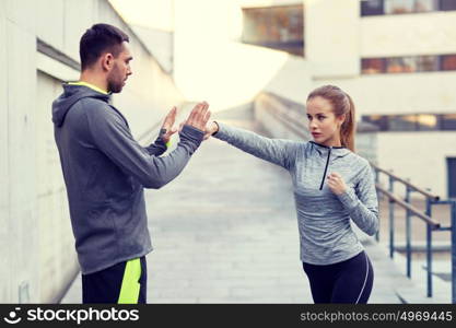 fitness, sport, martial arts, self-defense and people concept - happy woman with personal trainer working out strike outdoors. happy woman with coach working out strike outdoors