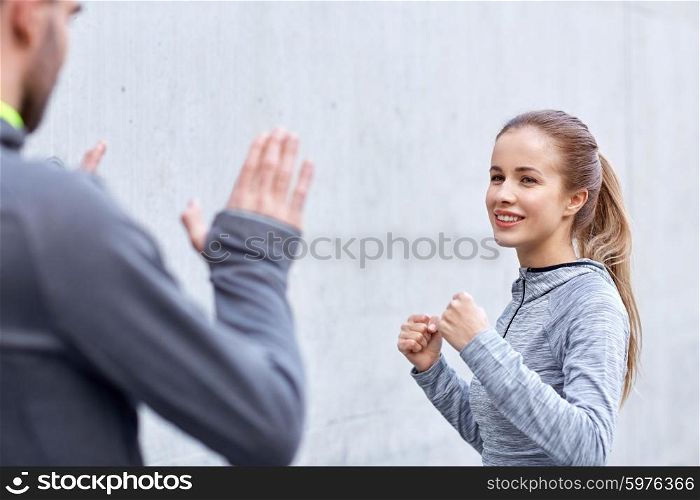fitness, sport, martial arts, self-defense and people concept - happy woman with personal trainer working out strike outdoors