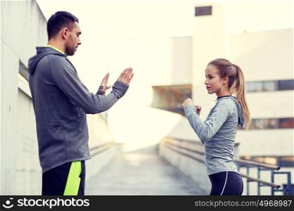 fitness, sport, martial arts, self-defense and people concept - woman with personal trainer working out strike outdoors. woman with coach working out strike outdoors